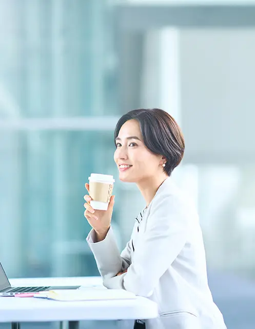 コーヒーを飲みながら仕事をしている女性社員