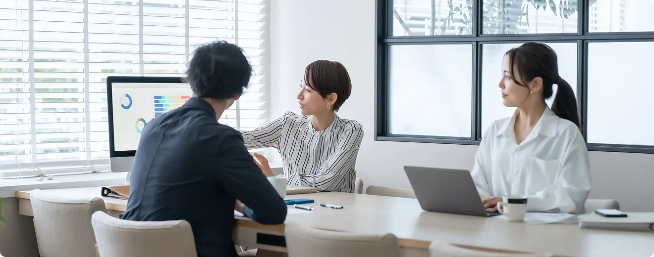 ディスプレイを見ながら打ち合わせている3人の社員