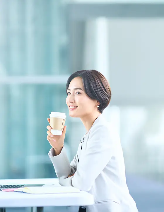 コーヒーを飲みながら仕事をしている女性社員