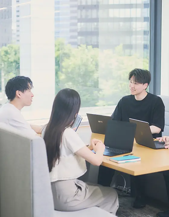 窓際のオフィスで打ち合わせをする若手社員