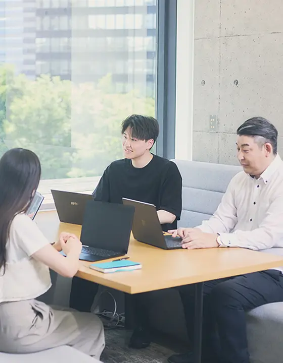 窓際のオフィスで打ち合わせをする4人の若手社員